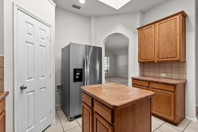 1060 Knightsbridge Dr, Frisco, TX 75036 - kitchen with stainless steel fridge with ice dispenser, arched walkways, light tile patterned floors, light countertops, and lofted ceiling