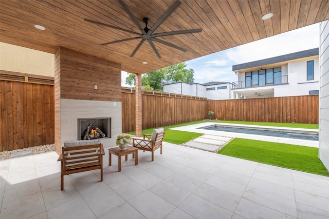 4435 Merrell Rd, Dallas, TX 75229 - fenced backyard with a warm lit fireplace, a patio, and a ceiling fan