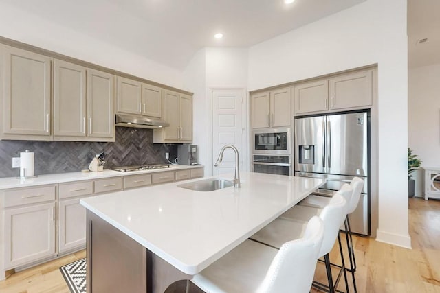 1033 Falls Rush Way, Royse City, TX 75189 - kitchen with appliances with stainless steel finishes, a sink, under cabinet range hood, decorative backsplash, and a kitchen breakfast bar