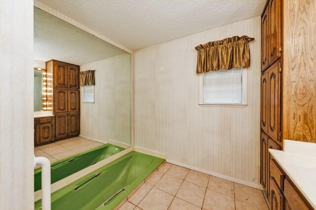 1300 Woodland Trail Dr, Bowie, TX 76230 - bathroom with vanity, a bath, a textured ceiling, tile patterned floors, and baseboards