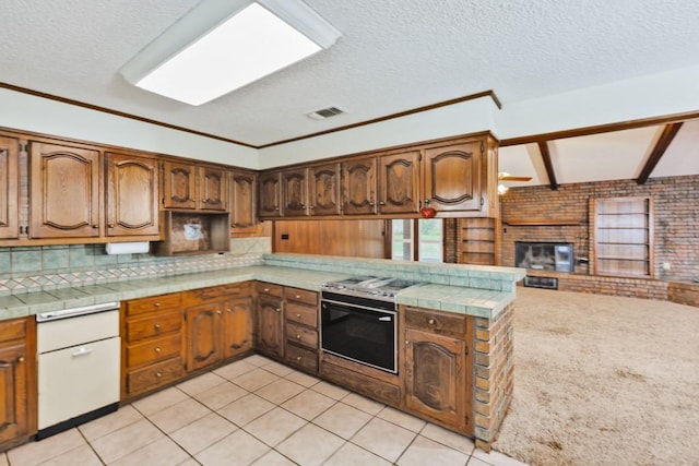 1300 Woodland Trail Dr, Bowie, TX 76230 - kitchen featuring stainless steel electric range, a textured ceiling, a brick fireplace, light tile patterned floors, and tasteful backsplash