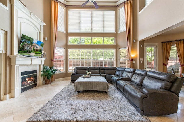 2048 Remington Ln, Frisco, TX 75033 - living area featuring a towering ceiling, ceiling fan, light tile patterned flooring, a glass covered fireplace, and baseboards