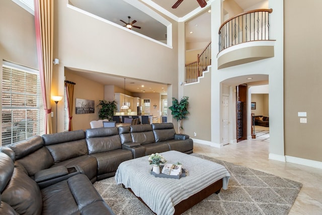 2048 Remington Ln, Frisco, TX 75033 - living room featuring a ceiling fan, a towering ceiling, light marble finish floors, baseboards, and arched walkways