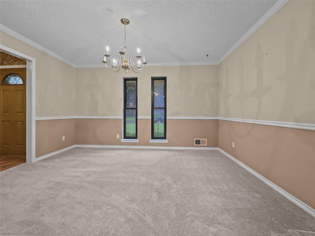 carpeted spare room with a textured ceiling, a chandelier, baseboards, and ornamental molding