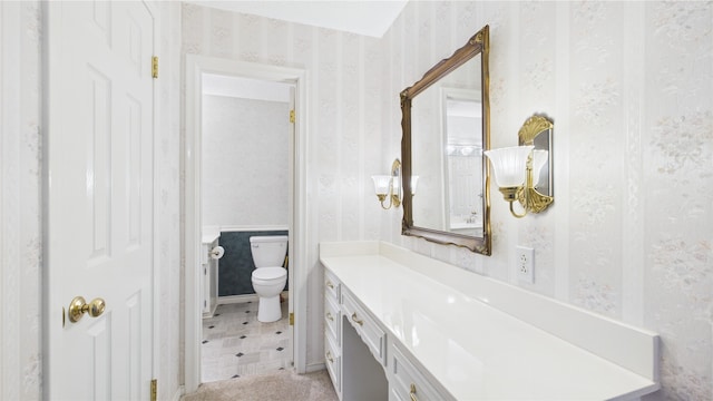 bathroom with wallpapered walls, toilet, and vanity