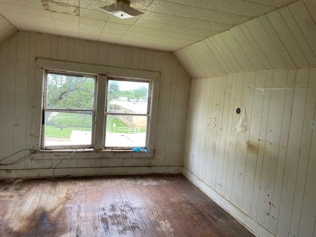 additional living space featuring hardwood / wood-style floors, lofted ceiling, and wooden walls