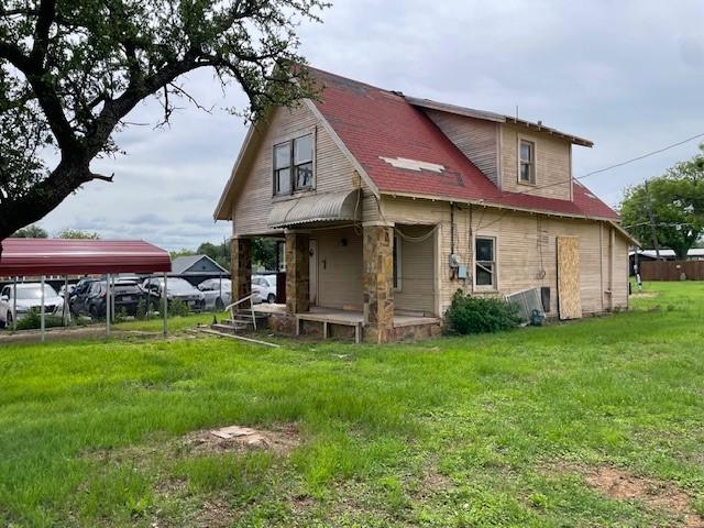 back of house with covered porch, a yard, and a carport