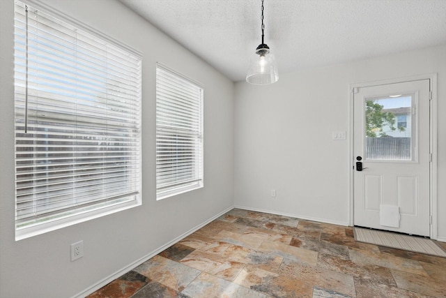 3110 Legend Dr, Mckinney, TX 75070 - unfurnished dining area with light stone finish floors, baseboards, and a textured ceiling