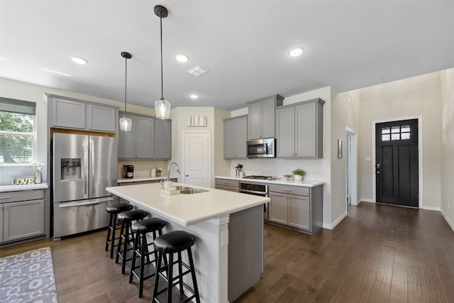 216 Shadow Creek Ln, Hickory Creek, TX 75065 - kitchen with stainless steel appliances, gray cabinetry, a sink, a breakfast bar area, and dark wood finished floors