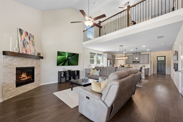 216 Shadow Creek Ln, Hickory Creek, TX 75065 - living room featuring a ceiling fan, a stone fireplace, dark wood finished floors, a towering ceiling, and baseboards