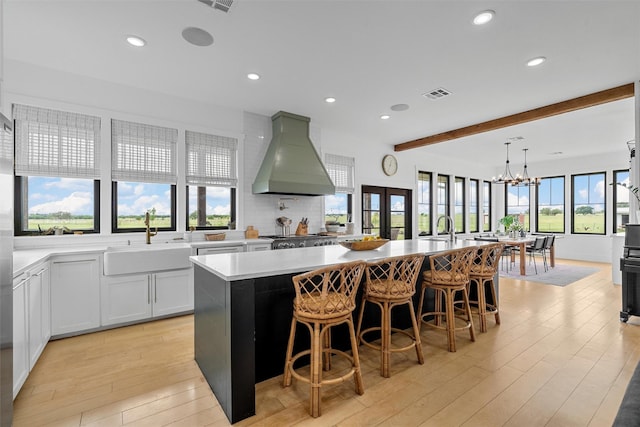 1197 Prairie Chapel Rd, Crawford, TX 76638 - kitchen featuring custom exhaust hood, a sink, beamed ceiling, light wood-style flooring, and a spacious island