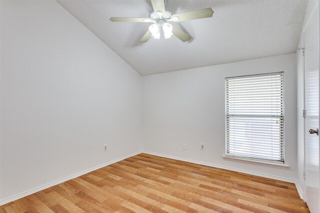 unfurnished room with lofted ceiling, light wood finished floors, a ceiling fan, and baseboards