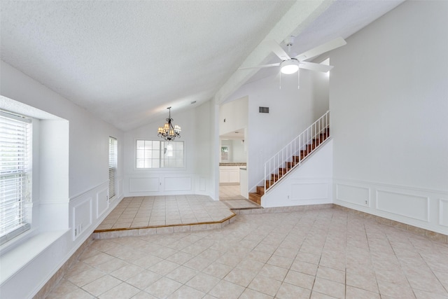 foyer entrance with a decorative wall, light tile patterned floors, a chandelier, lofted ceiling, and stairs