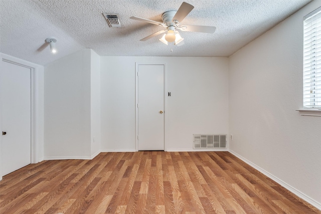 empty room featuring light wood-type flooring, a textured ceiling, and ceiling fan