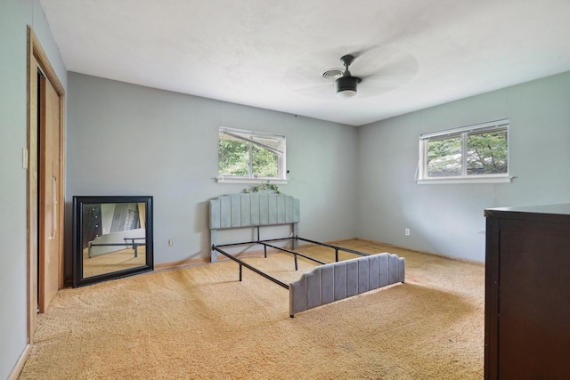 bedroom with multiple windows, carpet flooring, a ceiling fan, and a closet