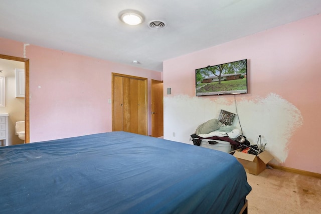 carpeted bedroom with ensuite bathroom, a closet, and baseboards