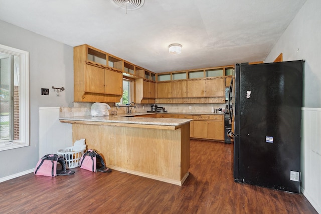 kitchen featuring freestanding refrigerator, a peninsula, dark wood-type flooring, light countertops, and tasteful backsplash