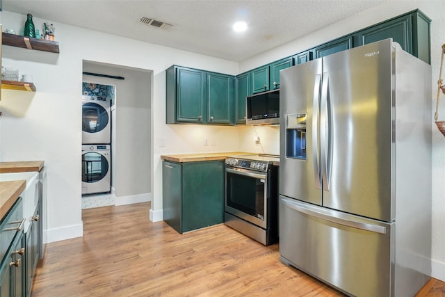 5012 Marina Del Rd, Fort Worth, TX 76179 - kitchen with stainless steel appliances, stacked washer / drying machine, butcher block counters, open shelves, and green cabinets