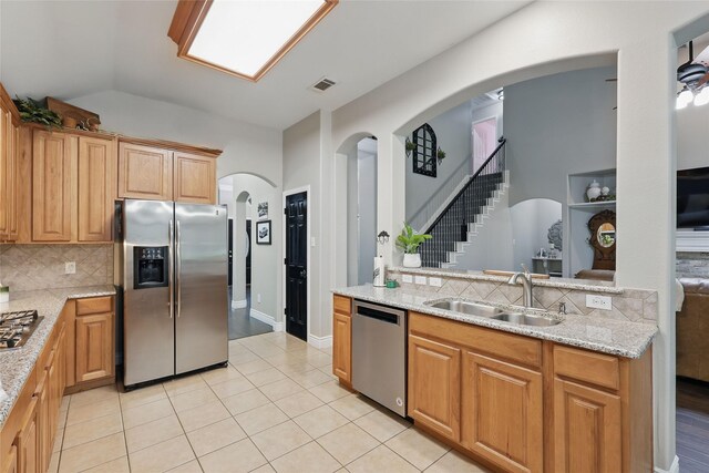 kitchen with stainless steel appliances, a sink, tasteful backsplash, light tile patterned flooring, and lofted ceiling