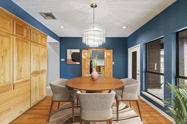 dining area featuring light wood-style flooring, a chandelier, baseboards, a textured ceiling, and recessed lighting