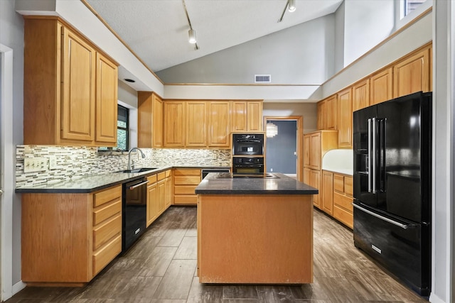 kitchen featuring black appliances, rail lighting, a center island, a sink, and backsplash