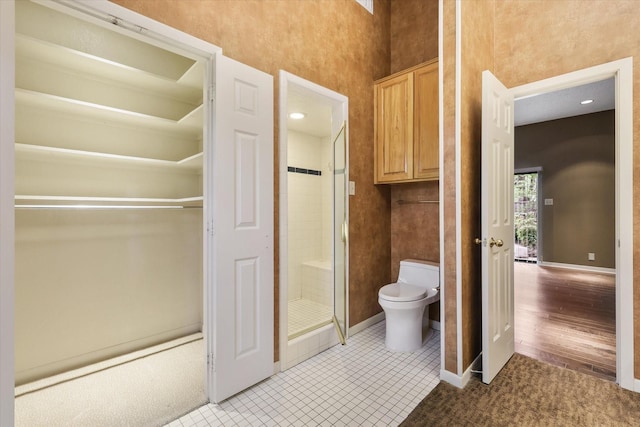 bathroom with toilet, a stall shower, and baseboards