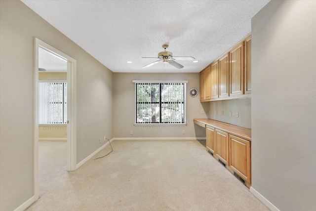 kitchen with ceiling fan, baseboards, light colored carpet, and a textured ceiling