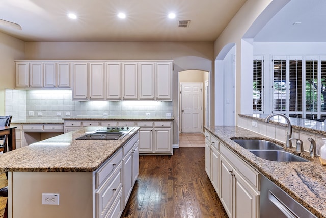 1430 Westmont Dr, Allen, TX 75013 - kitchen with arched walkways, black electric cooktop, a sink, dark wood-style floors, and light stone countertops