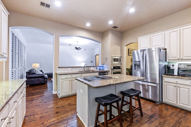 1430 Westmont Dr, Allen, TX 75013 - kitchen with stainless steel appliances, a sink, arched walkways, a ceiling fan, and a kitchen island