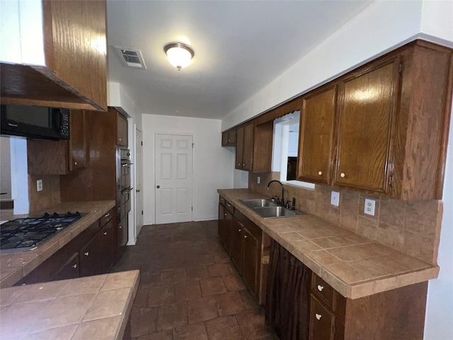 216 E Homewood Dr, Crockett, TX 75835 - kitchen featuring a sink, tile counters, gas cooktop, stone finish flooring, and backsplash
