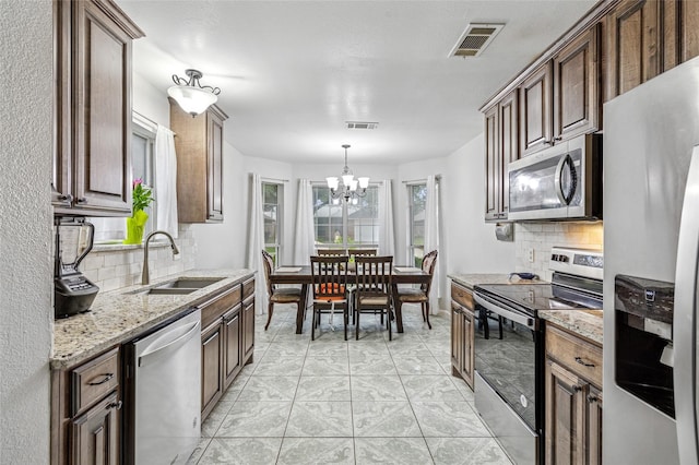 6405 Longmont Trl, Fort Worth, TX 76179 - kitchen featuring stainless steel appliances, a sink, tasteful backsplash, a chandelier, and light stone countertops