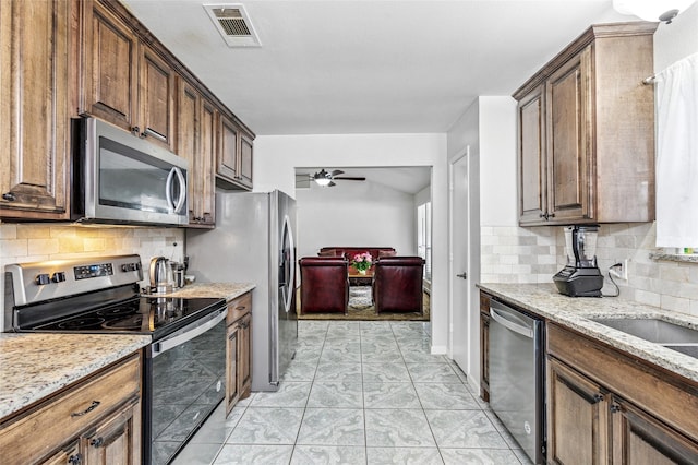 6405 Longmont Trl, Fort Worth, TX 76179 - kitchen with stainless steel appliances, ceiling fan, backsplash, and light stone countertops