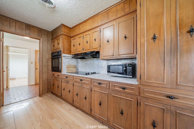1201 New Hope Rd, Stamford, TX 79553 - kitchen with black appliances, brown cabinetry, light countertops, backsplash, and under cabinet range hood