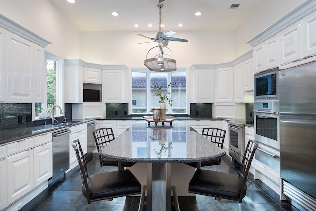 12229 Pecan Forest Dr, Dallas, TX 75230 - kitchen featuring appliances with stainless steel finishes, a sink, white cabinets, a breakfast bar, and recessed lighting