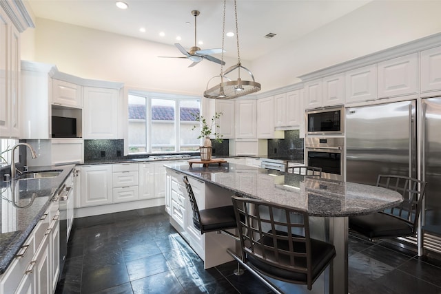 12229 Pecan Forest Dr, Dallas, TX 75230 - kitchen featuring a sink, built in appliances, a breakfast bar, a ceiling fan, and a kitchen island