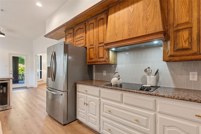 kitchen featuring black electric stovetop, stainless steel refrigerator with ice dispenser, wine cooler, tasteful backsplash, and light wood-style flooring