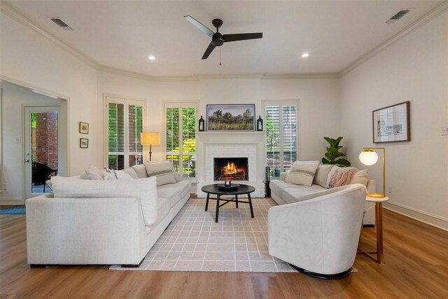 living room featuring plenty of natural light, light wood-style flooring, ornamental molding, a ceiling fan, and recessed lighting