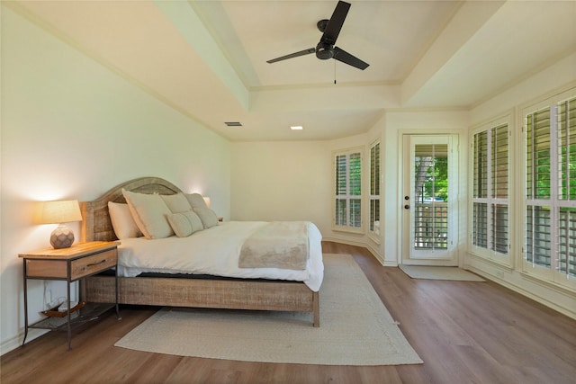 bedroom featuring a tray ceiling, access to outside, wood finished floors, a ceiling fan, and baseboards
