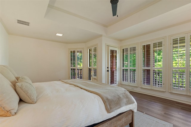 bedroom with wood finished floors, a ceiling fan, a raised ceiling, and ornamental molding
