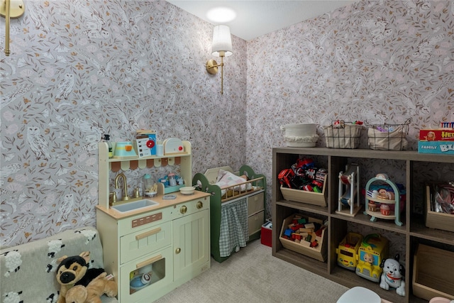 rec room with wallpapered walls, a sink, and light colored carpet