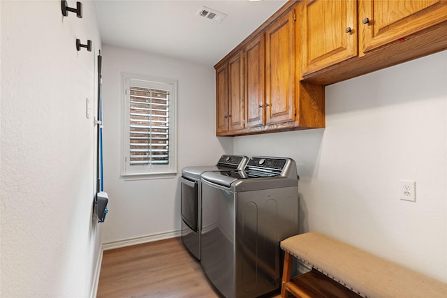 washroom featuring separate washer and dryer, cabinet space, baseboards, and light wood-style flooring