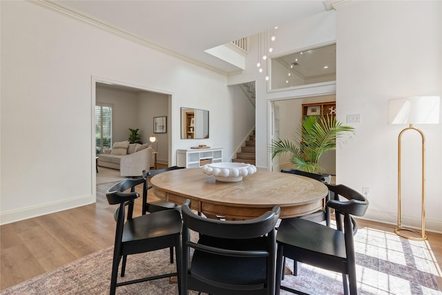 dining area with crown molding, stairway, light wood-type flooring, and baseboards