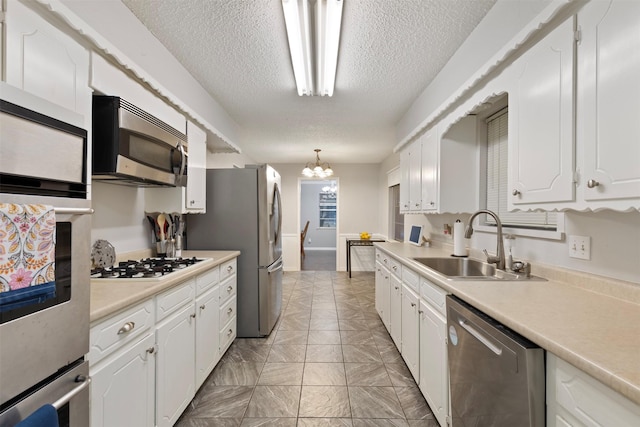 1317 Kingsbridge Dr, Garland, TX 75040 - kitchen featuring appliances with stainless steel finishes, a sink, a textured ceiling, white cabinets, and light countertops