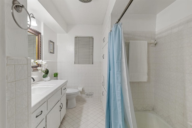 1317 Kingsbridge Dr, Garland, TX 75040 - full bath with tile walls, tile patterned floors, toilet, vanity, and shower / bath combo with shower curtain