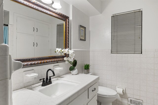 1317 Kingsbridge Dr, Garland, TX 75040 - bathroom with tile walls, toilet, vanity, and wainscoting