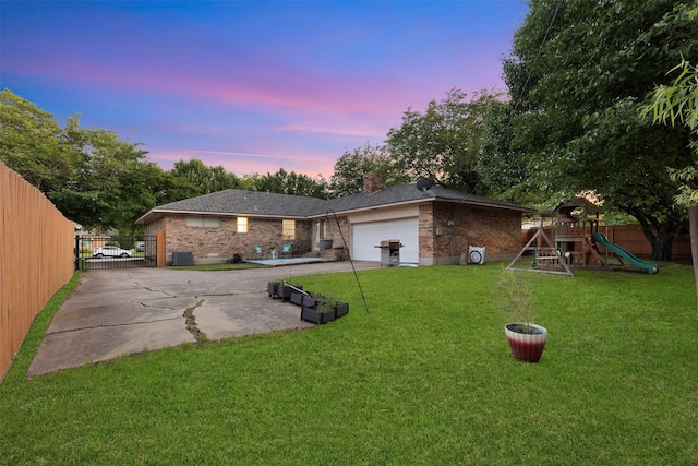 1317 Kingsbridge Dr, Garland, TX 75040 - back of property at dusk featuring brick siding, an attached garage, driveway, a gate, and a chimney