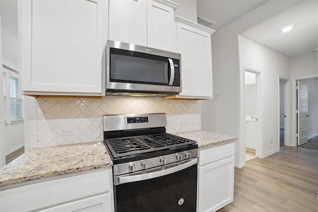 505 Pleasant Hill Ln, Fate, TX 75189 - kitchen featuring appliances with stainless steel finishes, tasteful backsplash, light wood-style floors, baseboards, and white cabinets
