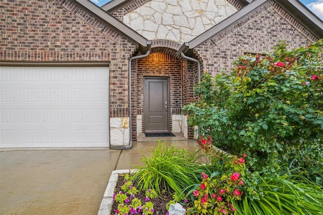 505 Pleasant Hill Ln, Fate, TX 75189 - view of exterior entry featuring a garage, concrete driveway, brick siding, and stone siding