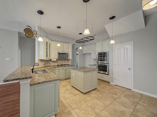 kitchen with appliances with stainless steel finishes, a sink, a peninsula, decorative backsplash, and glass insert cabinets
