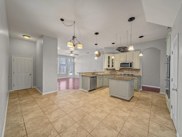 kitchen with appliances with stainless steel finishes, a peninsula, tasteful backsplash, light tile patterned floors, and ceiling fan